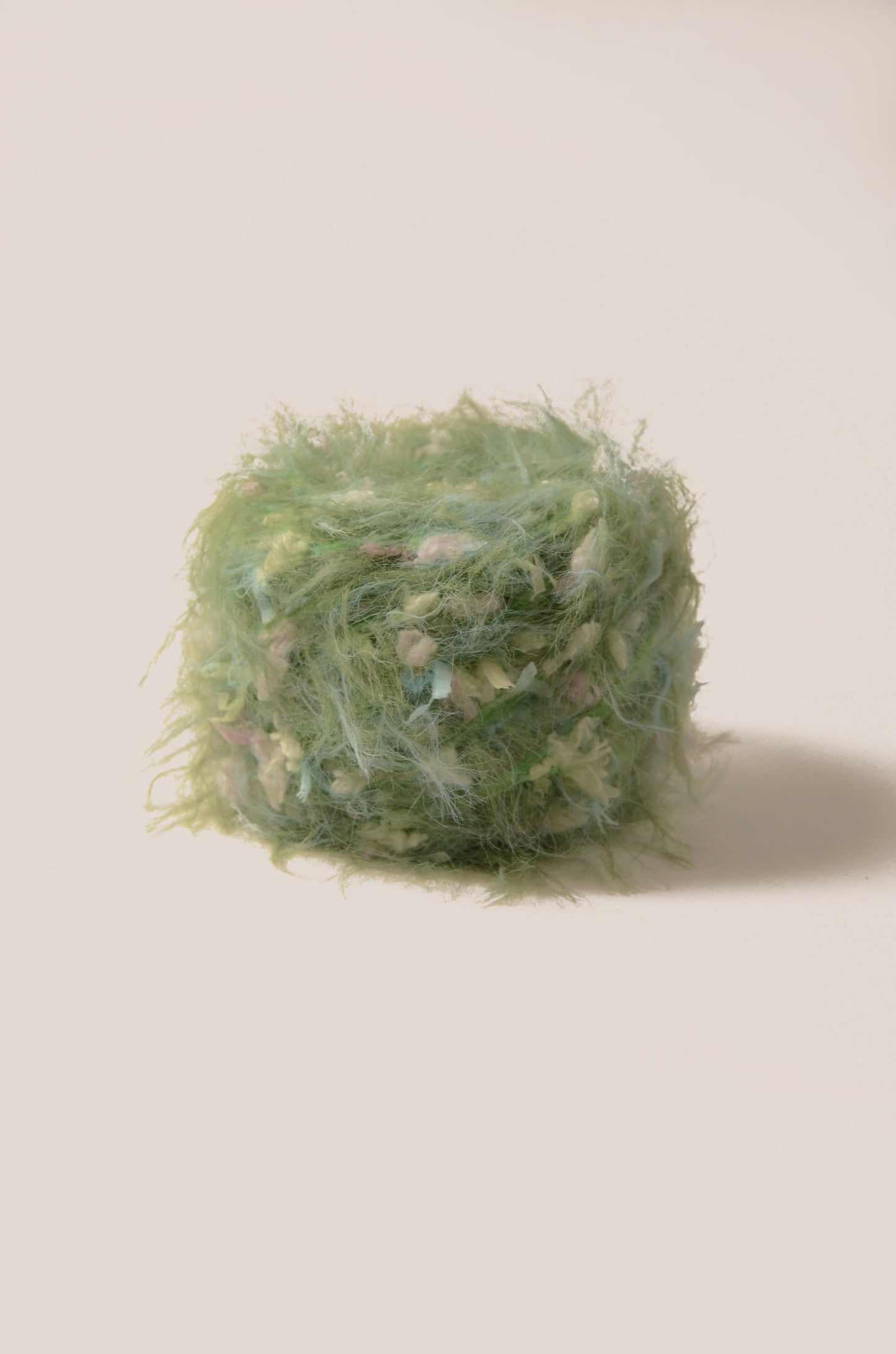 Mossy Meadow hand-blended yarn – yellow-green base with pastel blue, pink, and yellow threads, soft fluffy texture inspired by wild meadow flowers
